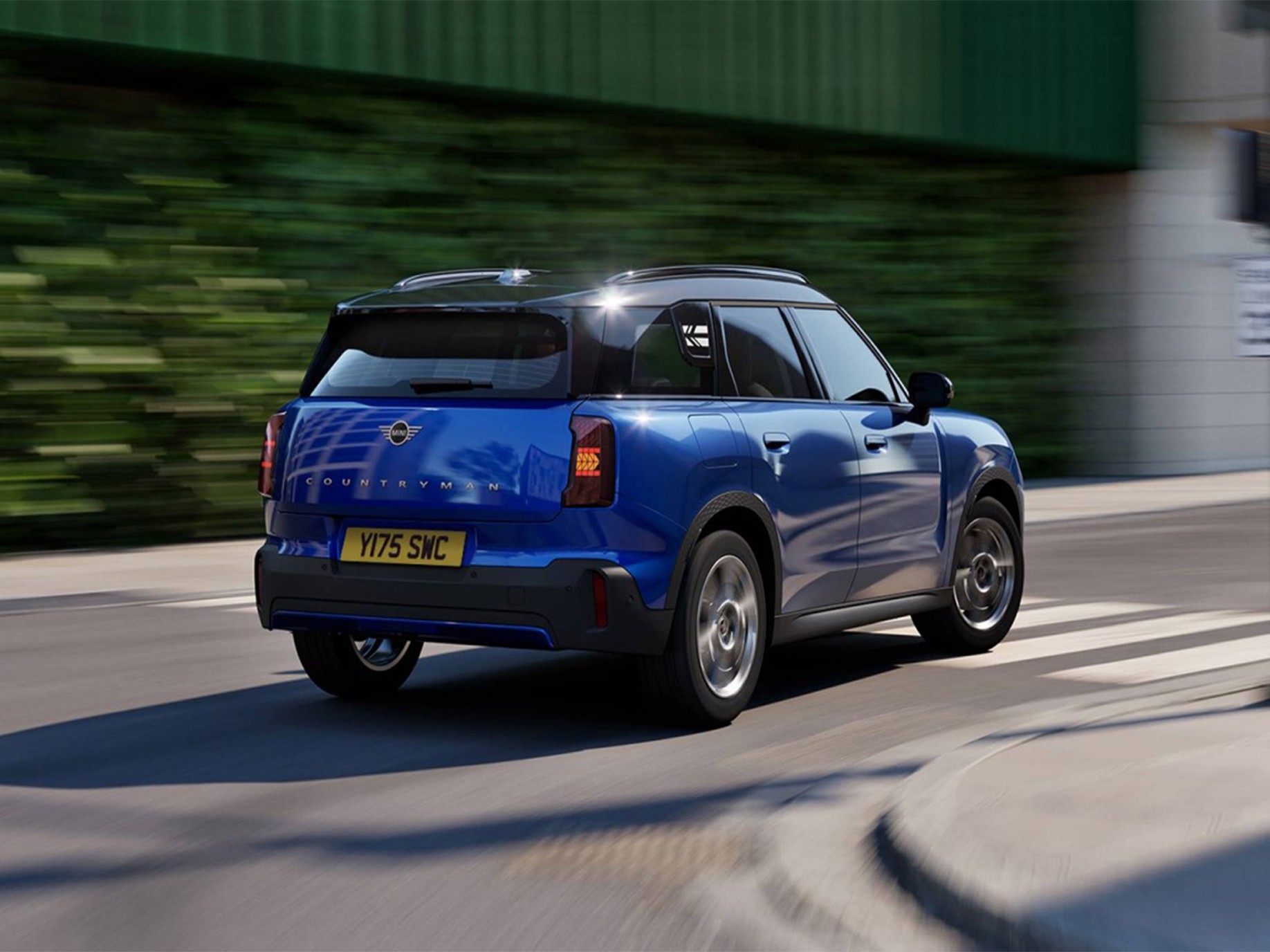 Side rear view of the MINI Countryman in Nanuq White with Black Roof standing on a street.